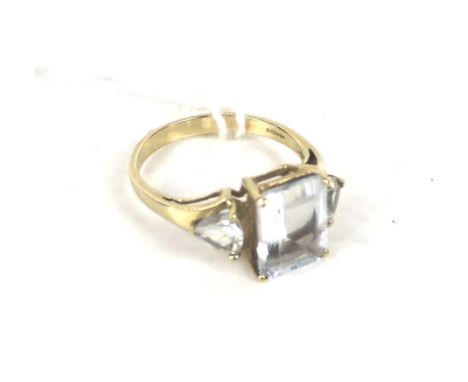 A modern 9ct gold and aquamarine three stone ring. Centred with a rectangular step-cut aquamarine between brilliant-cut aquam