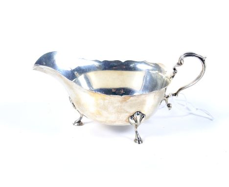 A vintage small silver sauce boat. With a flying scroll handle, a shaped rim and three hoof feet, hallmarks for Birmingham 19