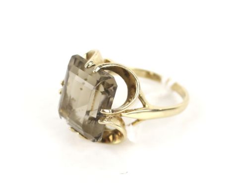 A vintage 9ct gold and smoky quartz single stone ring. The rectangular step-cut stone in an open four twin-claw setting onm a