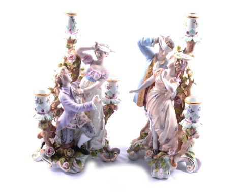 A pair of three light figural porcelain candelabra, Blind Man's Buff, naturalistic floral and foliate base, fixed sconces, cr