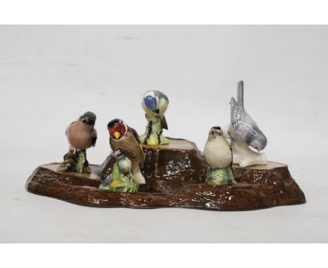 A BESWICK TREE STUMP STAND WITH A COLLECTION OF SMALL BESWICK BIRDS TO INCLUDE A CHAFFINCH, BLUE TIT, WREN, GOLDCREST AND GOL