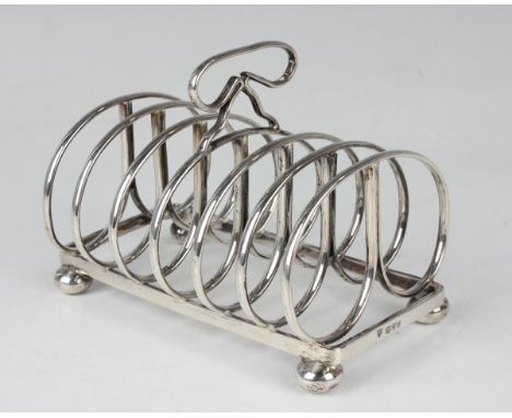 An Edwardian silver six-division toast rack with a loop shaped handle, raised on four bun feet, Chester 1903 by Haseler Broth