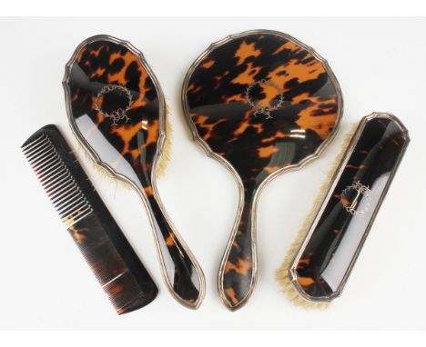 A George V silver and tortoiseshell dressing table set, comprising hand mirror, hairbrush, clothes brush and tortoiseshell co