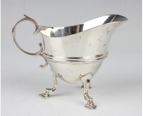 A late Victorian silver helmet form cream jug with scroll handle and horizontal girdle, on scroll legs and hoof feet, London 