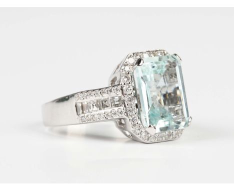 A white gold, aquamarine and diamond cluster ring, claw set with the large cut cornered rectangular step cut aquamarine withi