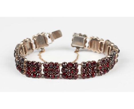 A gilt metal and Bohemian garnet bracelet, formed as a row of nine stone square panel shaped links, on a snap clasp, length 1