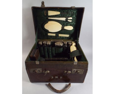 A Late 19th Century Lidded Crocodile Skin Fitted Travelling Case Containing Various Silver Topped Glass Bottles, Ivory Brushe