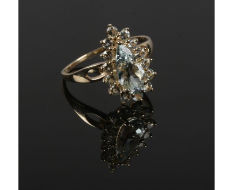 A 10ct gold cluster ring set with pale blue / green gemstones, with one large pear cut stone under a border of brilliant cut 