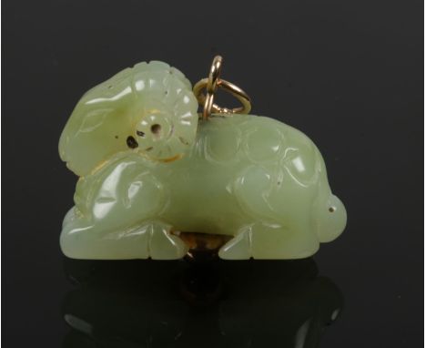 A Chinese Qing dynasty carved pale celadon jade carving of a recumbent ram. Drilled and on a later applied gold suspension lo