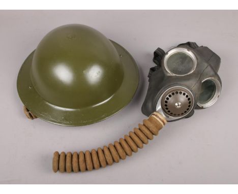 A military Brodie type helmet, along with a WWII gas mask stamped Avon 1-41 and baring the broad arrow mark to the head strap