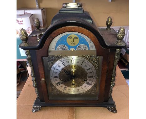 An Urgos arch topped bracket clock in a walnut-style case with ormulu mounts and finials, a silvered chapter ring and moon ph