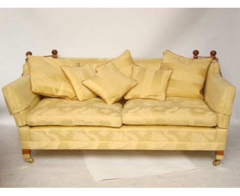 A modern Knole style two seated sofa with low back and sides on brass capped forelegs on casters, with two squab cushions uph