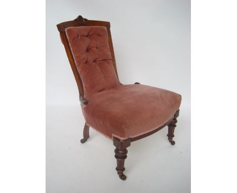 A Victorian walnut framed ladies chair, with buttonback upholstery and serpentine seat, on turned tapering forelegs and ceram