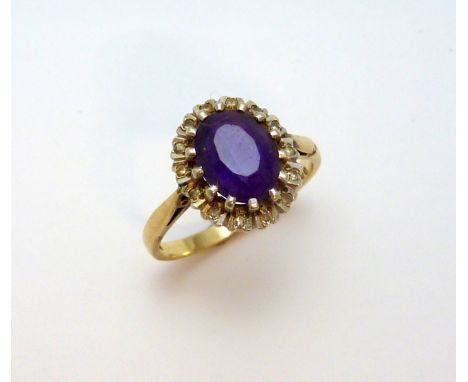 A 9CT GOLD AMETHYST AND DIAMOND RING, the oval amethyst within a surround of diamond accents, to the plain tapered band, hall