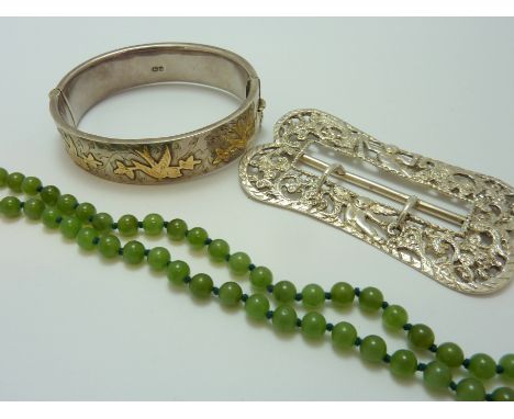 THREE ITEMS, to include a decorative silver belt buckle, a string of jade beads and a silver and gold hinged decorative bangl