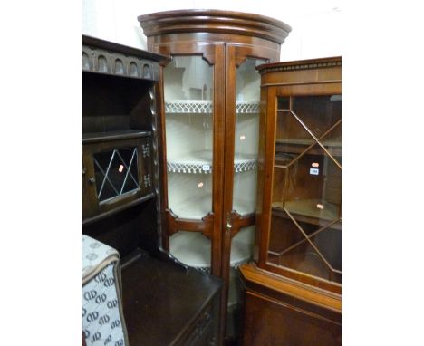 A MAHOGANY GLAZED BOW FRONTED TWO DOOR CORNER CUPBOARD