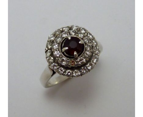 A RUBY AND DIAMOND RING, the circular ruby within two surrounds of brilliant cut diamonds, to the plain tapered band, estimat