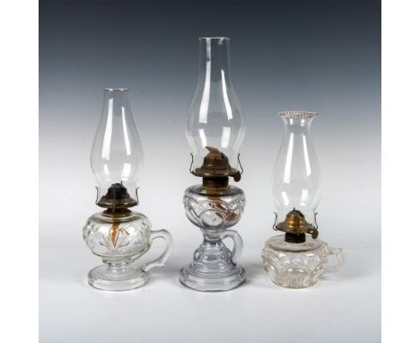 Assorted glass and brass oil-burning lamps, including three glass oil lanterns with hurricane glass. These lamps boast glass 