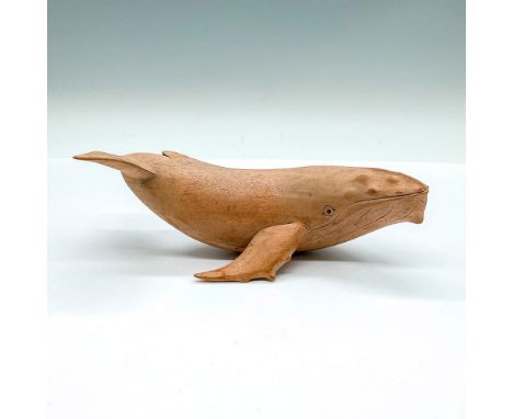 A small light wood carving of a humpback whale. Dimensions: 7"L x 3.25"W x 2.75"HCondition: Age related wear.