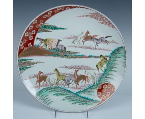 A large and round plate hand painted in green, iron-red, purple, yellow, and gilt enamel. Features a herd of horses running t
