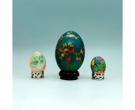 A set of three decorative eggs with fauna and foliage designs painted beautifully onto each item. One is a large green egg wi