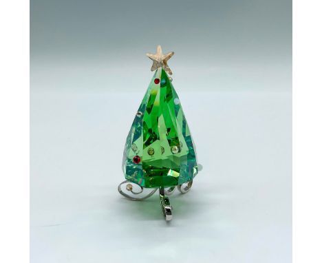 A whimsical small Christmas tree in a peridot crystal with red, clear, and white crystal accents. A light golden crystal star