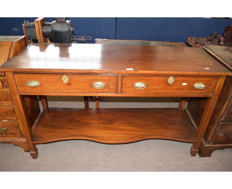 An Edwardian mahogany side table with two frieze drawers and tapering square legs with a serpentine base shelf, 139cm wide