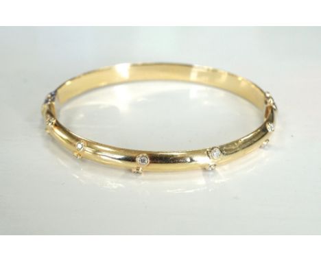 DIAMOND SET FOURTEEN CARAT GOLD BANGLEthe hinged bangle set with ten diamonds and with safety clasp, approximately 4.4 grams