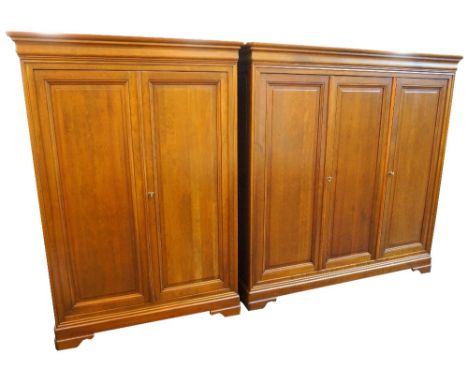 TWO GRANGE LARGE OAK WARDROBESwith moulded cornices above panelled doors opening to reveal fitted interiors, standing on brac