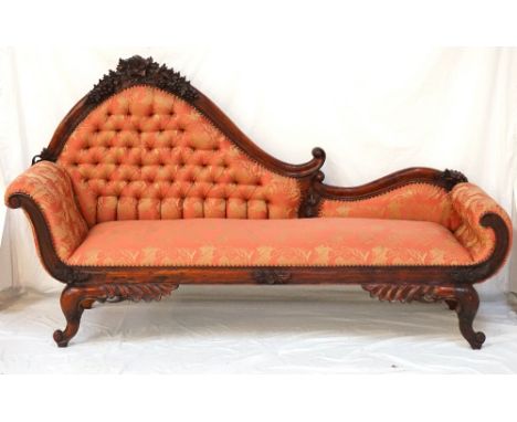 LARGE TEAK CHAISE LONGUEthe shaped button back decorated with carved grapes and flower heads, with shaped roll ends, standing