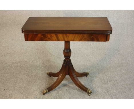A George III style mahogany card table, the foldover top with a green baize lining on a quatraform base with brass lion paw c
