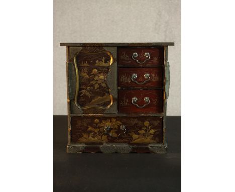 A Japanese Meiji period lacquered tabletop cabinet, painted with gilded flowers and landscapes, with one loose door partially