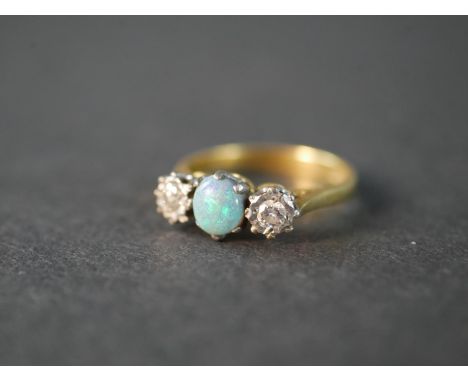 An 18 carat yellow gold and platinum Edwardian opal and diamond three stone ring, set to centre with an oval opal cabochon wi