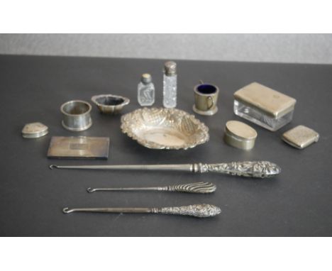 A collection of assorted silver items, including three boot hooks, a repousse design silver dish, a silver card holder, napki