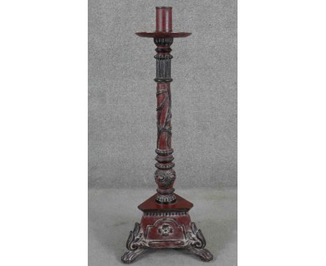 A Vietnamese floor standing candlestick, painted in hues of red and black, the reeded stem with beaded rings, on a tri-form b