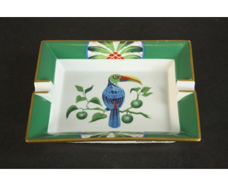 A Hermes porcelain ashtray, with a green and gilt border, centred by a toucan on a branch. H.4 W.19.5 D.16cm. 