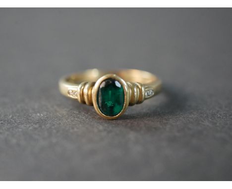 A 9 carat gold emerald paste and diamond flanked solitaire ring, set with four round eight cut diamonds, two to each shoulder