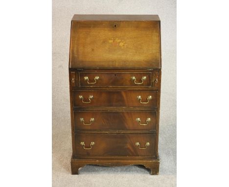 A George III style mahogany bureau, the fall front enclosing a drawer and pigeonholes, over four long graduated drawers on br