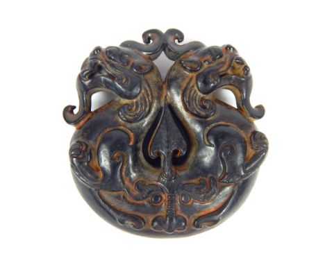 A late 19th century Chinese carved black jade circular amulet of two dragons opposing eachother, 5cm wide