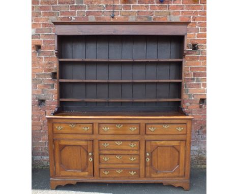 A 19TH CENTURY OAK DRESSER, the base with an arrangement of six short drawers and a cupboard to either side, raised on shaped