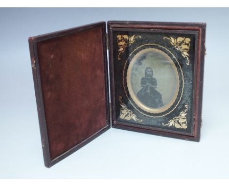 A 19TH CENTURY AMBROTYPE PORTRAIT IMAGE OF A YOUNG GIRL HOLDING LACEWORK, contained within a hinged frame with leather outer,