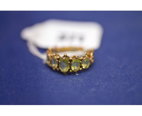 A five stone graduating green sapphire ring, ornate scrolling yellow metal shank.