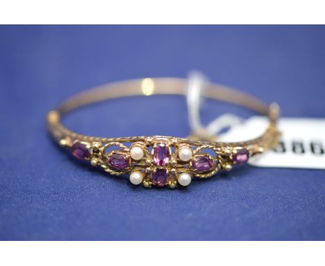 A Victorian style bangle set with pink stones, probably sapphire, and cultured pearls, in 9ct. yellow gold mount, scrolling a