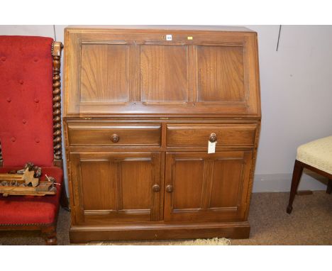 An Ercol elm bureau, the fall-flap opening to reveal pigeon holes and a drawer, above two short drawers, two cupboard doors b