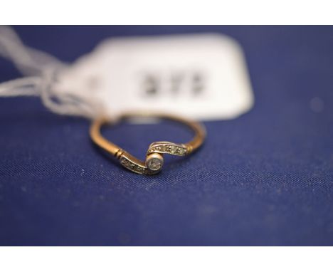 A diamond and 18ct. yellow gold bypass ring, the central stone surrounded by six smaller stones, 2.3grms gross.