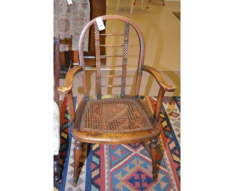A stained wood open arm elbow chair, with ladder back and shaped arms over a cane seat.