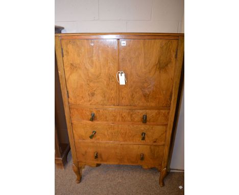 A 1930's walnut cabinet, cupboard doors opening to reveal a shelf above three graduating drawers, raised on cabriole legs, 76