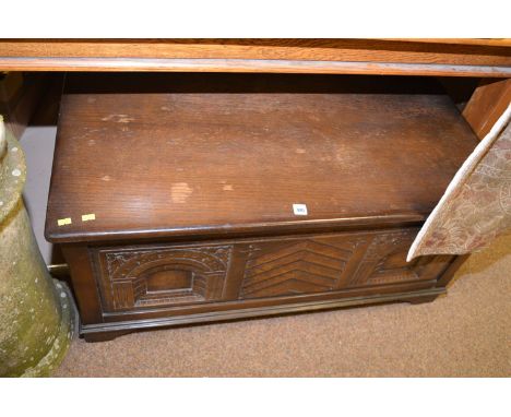 A modern dark stained and carved oak blanket box, with decorative carved front panel, raised on bracket feet, 102cms wide.