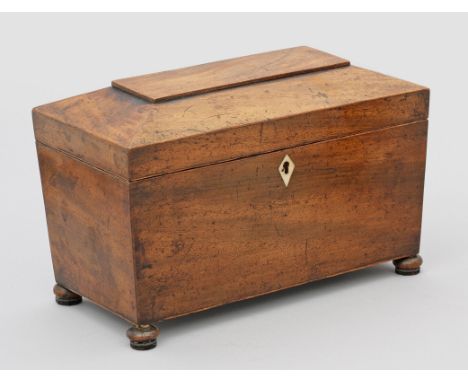 Tea-CaddyMahagoni, furniert, Knochenbeschlag. Querrechteckig angelegter, leicht konischer Korpus mit schräg ansteigendem Deck