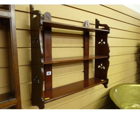 An Edwardian mahogany three shelf rack with fretwork floral ends